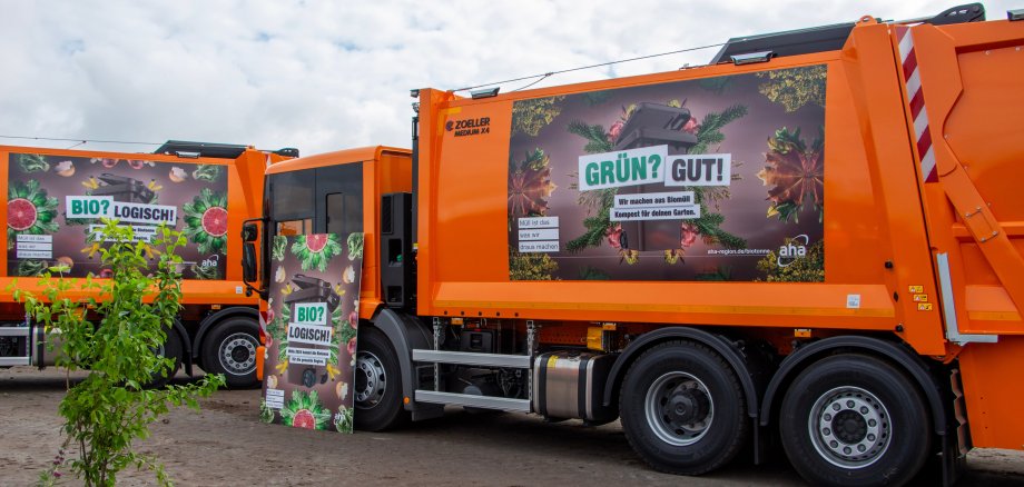 Aufnahme eines orangenen Müllwagens, der mit dem Kampangenmotiv zur Einführung der Biotonne im Umland bedruckt ist.